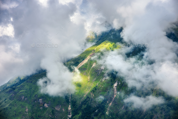 Mountains with green forest in clouds in overcast day - Stock Photo - Images