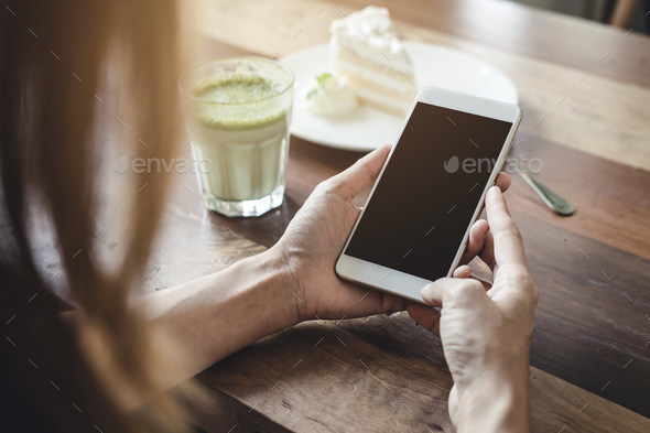 Young woman using smart phone and eating cake in cafe - Stock Photo - Images