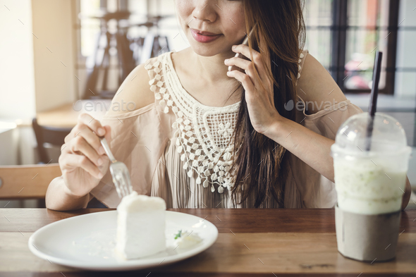 Young woman using smart phone and eating cake in cafe - Stock Photo - Images