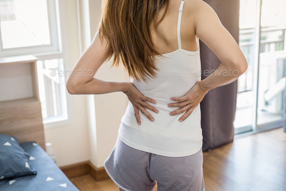 Woman suffering from back ache on the bed - Stock Photo - Images