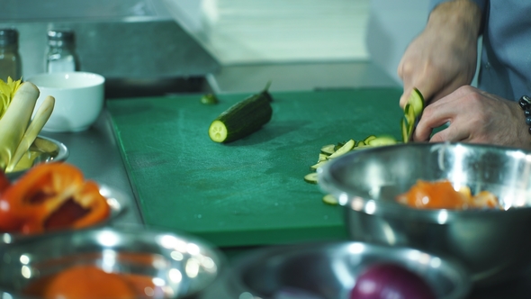 Chef Hands with Knife Cutting Vegetables on Board