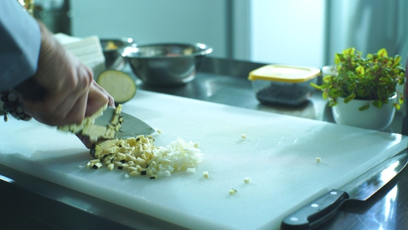 A Professional Chef Quickly Cuts Eggplants on the Board Using a Knife