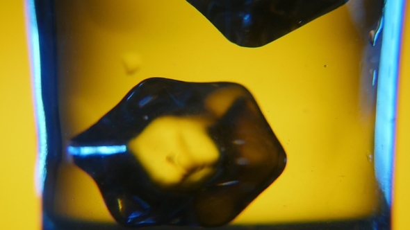 Five Big Cubes of Ice Are Thrown Into a Glass with Refreshing Water in Studio