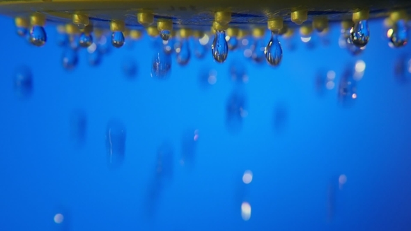 Hundreds of Sparkling Drops Fall From a Shower Nozzle in a Blue Bathroom