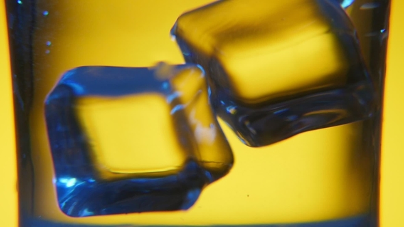 Several Cubes of Ice Are Thrown Into a Glass with Transparent Water in Studio