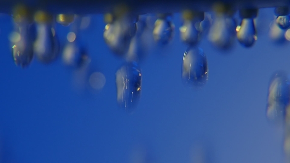 Cheerful Water Droplets Come Down From a Shower Nozzle in a Blue Bathroom