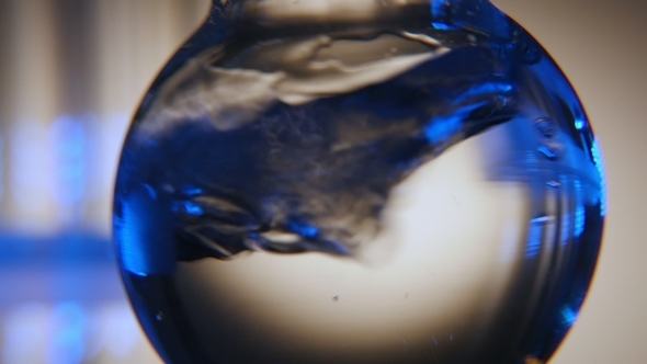 Bluish Water Is Shaken in a Round Bottom Flask in a Chemical Laboratory