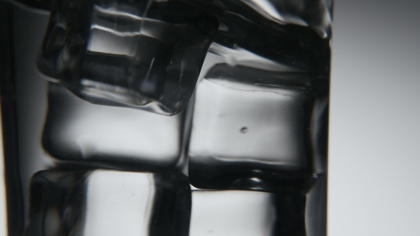 Gray and White Ice Cubes Are Shaken in a Crystaline Glass in the Grey Background