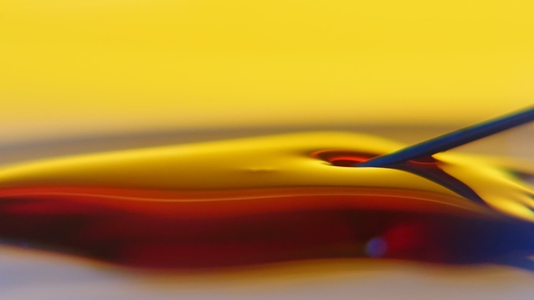 Metallic Needle Pierces the Red Liquid Surface in the Yellow Background