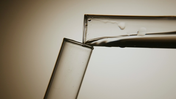 Distilling Water Is Poured From One Test Tube Into Another in a Chemical Lab