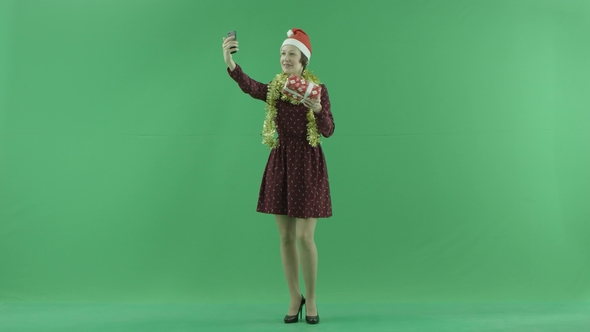 A Young Woman Is Making Selfies with Her Christmas Gift on the Green Screen