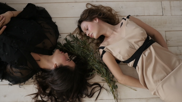 Two Beautiful Women Are Lying on the Floor