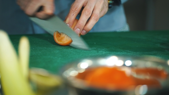 Chef Cutting Tomato on Board with More Veggies Around