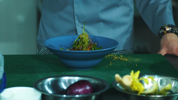Male Chef Adding Spices To Salad in Kitchen,