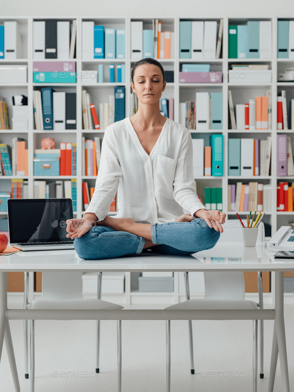 Woman practicing meditation on a desk - Stock Photo - Images