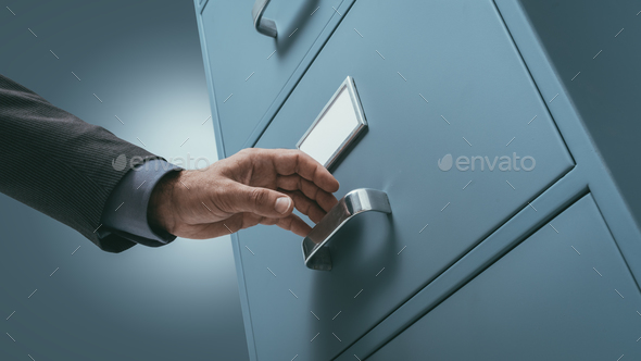 Office clerk searching files in the filing cabinet - Stock Photo - Images