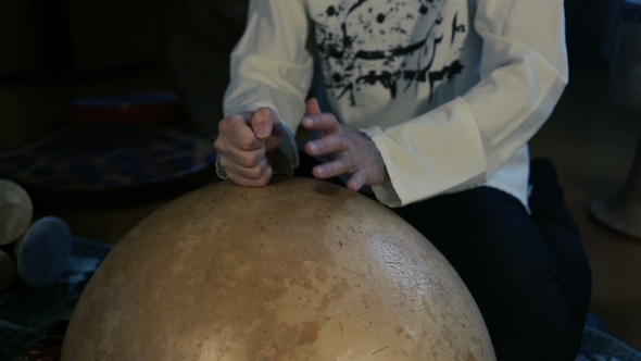 Man Drumming Out a Beat on an Arabic Percussion Drum Named Calabasse at Home.