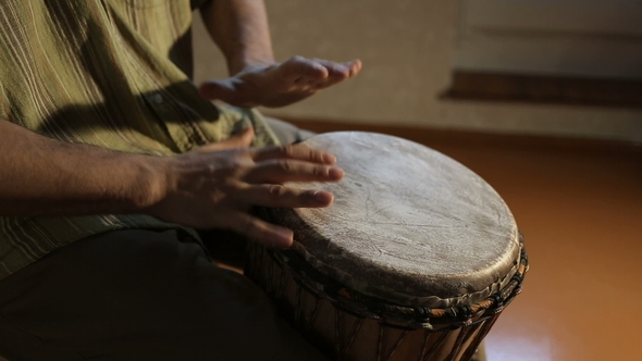 Man Who Drumming Out a Beat on an African Skin-covered Djembe By Hands