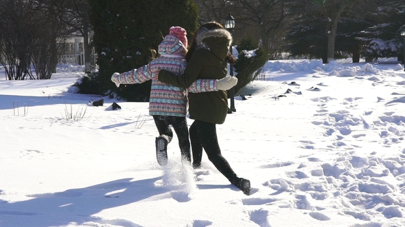 Happy Family Mother and Baby Girl Daughter Run, Walk Playing in Winter Outdoors in the Snow