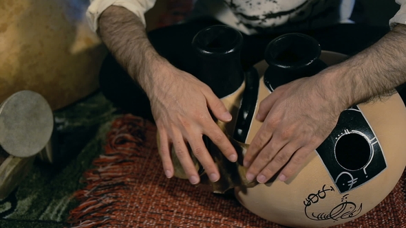 Man Drumming Out a Beat on an Arabic Percussion Drum Named Frudu