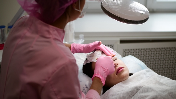 Beautician Removes Paint Residues with Cleaning Cloth From Eyebrows Girl