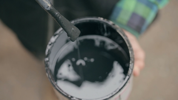 Painter Stirring a Paint in a Jar on the Street