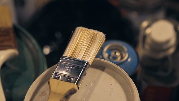 Brushes and Cans with Paint and Jars with Solvent in the Artist's Studio.