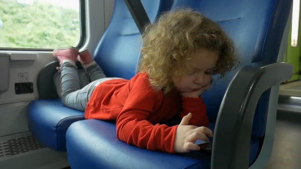 Child in Train Looks at Smartphone