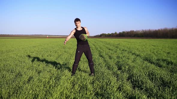 Front View of Muscular Young Man Engaged in Lifting in the Open Area alt