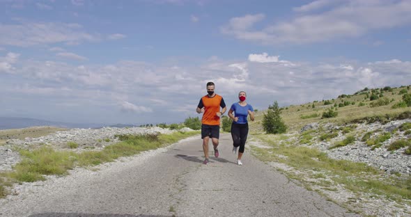 Young Couple in Medical Face Masks Running on the Road During a Pandemic alt