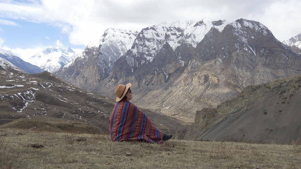 Woman Wrapped in Blanket Sitting in the Mountains