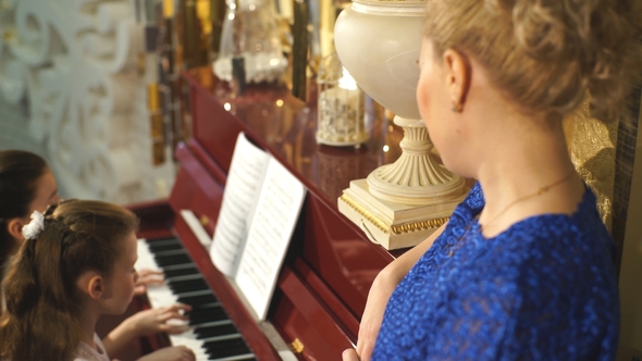 Family, Mother and Daughters Learn To Play Piano Together in Home