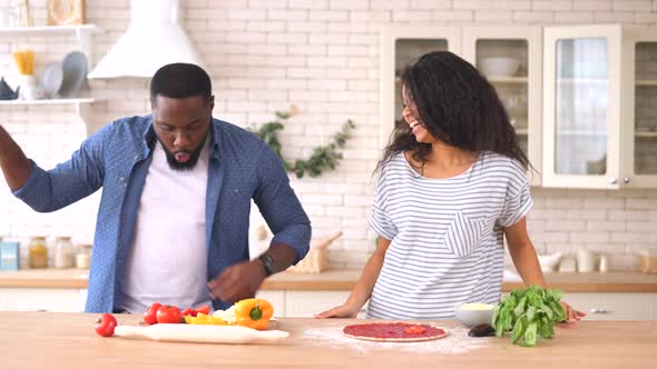Happy Multiracial Couple Preparing Pizza Together at Home alt