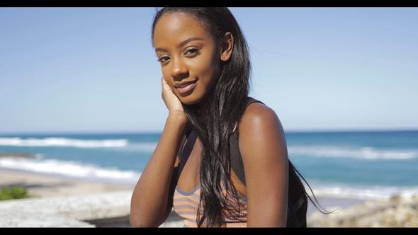 Smiling Young Woman Sitting at Ocean