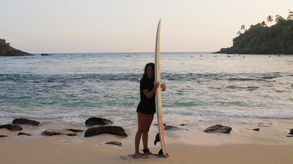 Girl Has Fun with Surfboard by the Ocean
