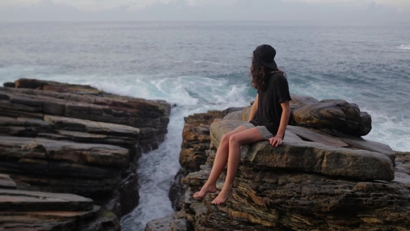 The Girl Is Seating on the Rocks Near the Ocean
