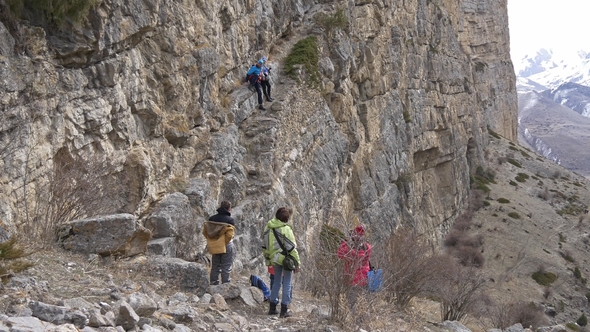 Group of Tourists on a Halt Near a Rock Wall