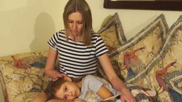 Young Mother Checking Temperature of Sick Daughter Lying in Bed