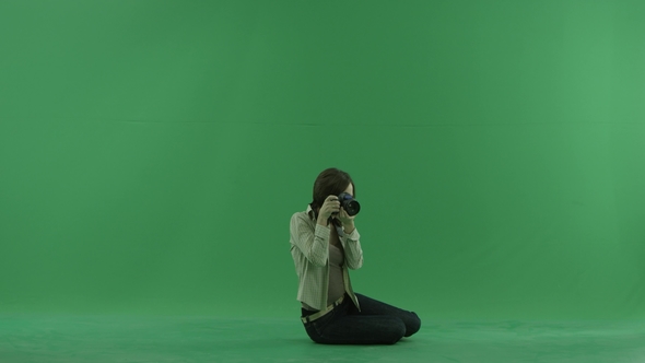 Sitting Young Woman Is Taking Photos on the Right Hand Side on the Green Screen