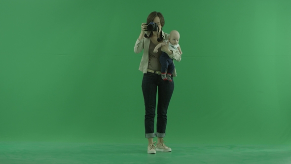 A Young Woman with Her Child Taking Photos Around Herself on the Green Screen