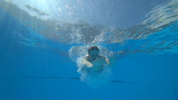 Young Woman Jumps in Blue Poolside and Swims with Open Eyes Underwater ...