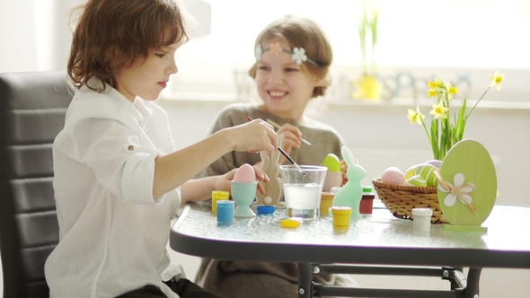 A Boy and a School-Age Girl Paint the Easter Eggs with Blue and Yellow Paint. Children's Creativity