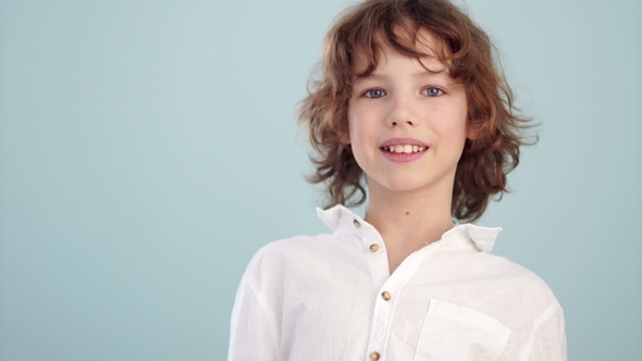 White Shirt on the Teenager. Beautiful Caucasian Smiling Child, on a Light Blue Background alt