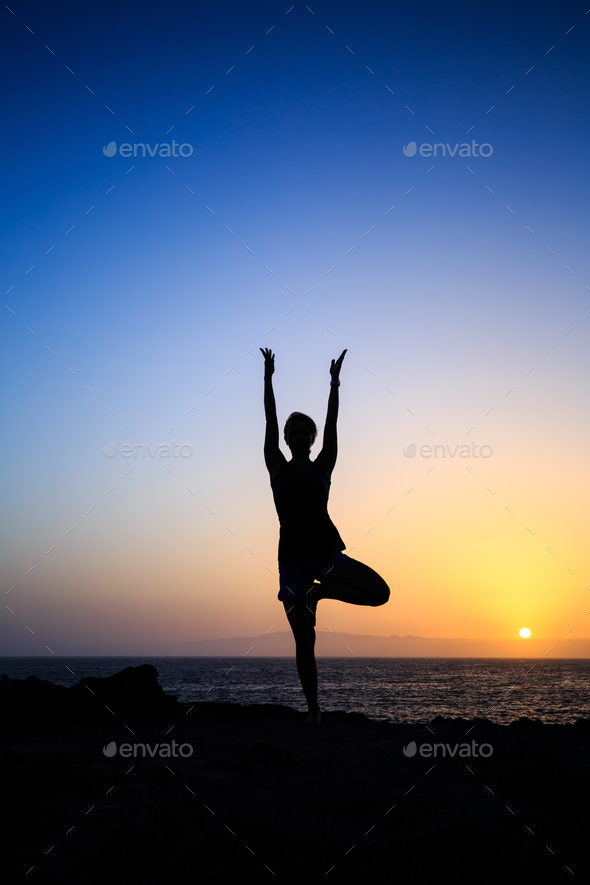 Silhouette of a woman practicing the tree yoga pose on a beach at sunset  during summer vacation Stock Photo | Adobe Stock