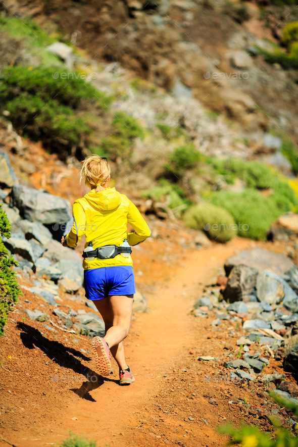 Young woman running in mountains on sunny summer day - Stock Photo - Images