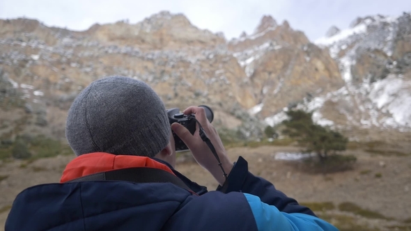 Man Takes a Picture on a Camera in the Mountains
