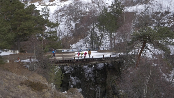 Group of Tourists on a Bridge Over a Mountain River