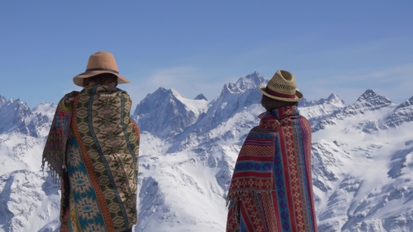 Two Women in Woolen Blankets Stand and Look at the Mountains