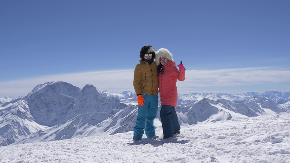 Cheerful Guy with a Girl Posing in the Snowy Mountains