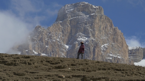 Man in a Poncho Near a Big Cliff